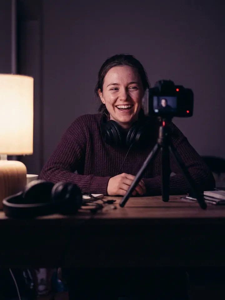A creator laughing while filming a video at her desk